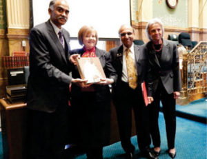Consul General of India Mr. P. Harish presenting a book on Gandhi to the Speaker of the House, Dickey Lee Hullinghorst while Rep Janak Joshi looks on