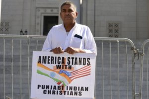 Krishan Sharma, holding a sign at the protest.